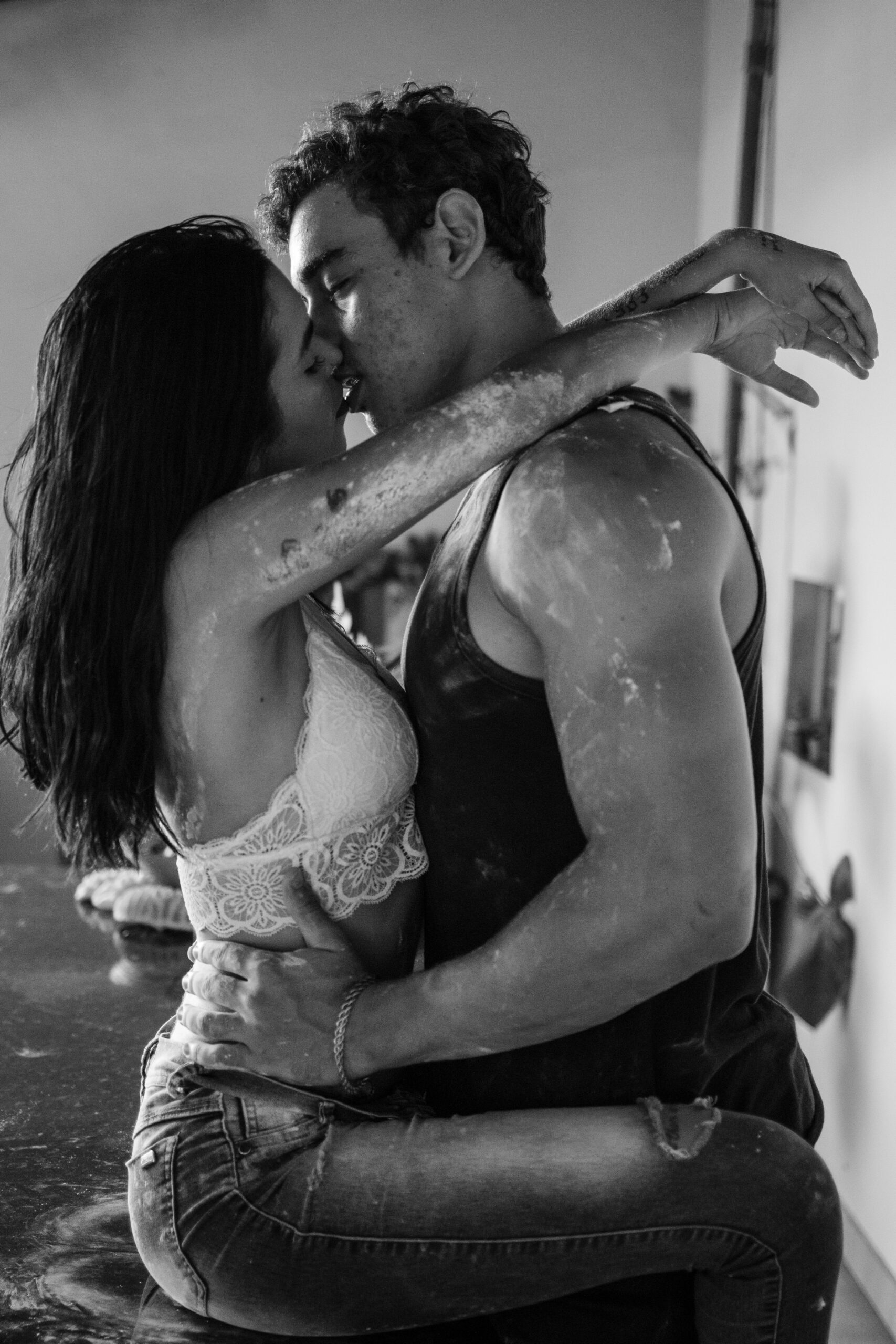 Intimate black and white photo of a couple sharing a passionate embrace indoors.